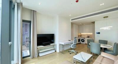 Modern open plan living room with kitchen, featuring sleek furnishings and natural light