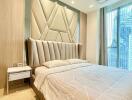 Modern bedroom with large bed and stylish headboard in a high-rise apartment