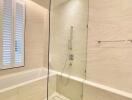 Modern bathroom with large bathtub, glass shower, and beige tiles