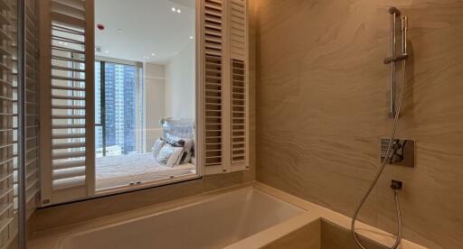 Modern bathroom with external view through window shutters, including bathtub and tasteful fixtures