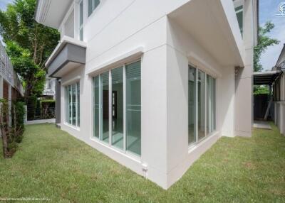 Modern residential building exterior with large windows and landscaped garden