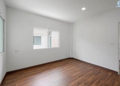 Spacious empty bedroom with wooden flooring and natural light