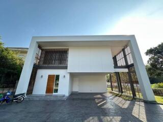 Modern white two-story house with large overhanging roof and expansive paved driveway