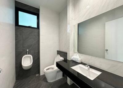 Modern bathroom with wall-mounted urinal, toilet, and sleek vanity