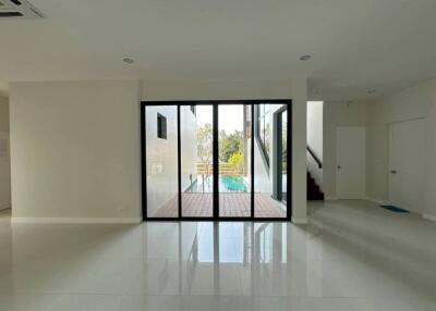 Spacious modern living room with large glass doors leading to a pool