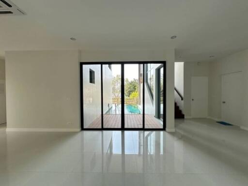 Spacious modern living room with large glass doors leading to a pool