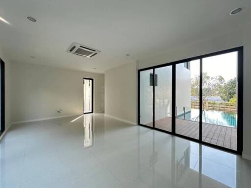 Spacious modern living room with large sliding glass doors leading to a swimming pool