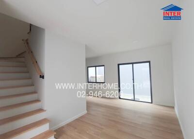 Spacious and bright living room with large windows and staircase