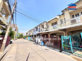 Exterior view of row houses with a clear blue sky and quiet street