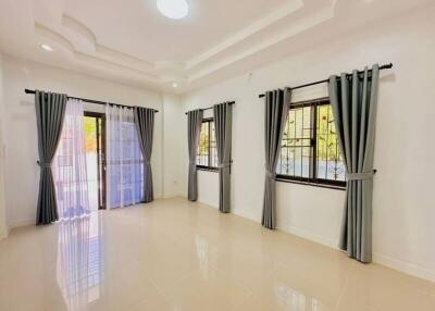 Spacious and brightly lit living room with large windows and elegant curtains