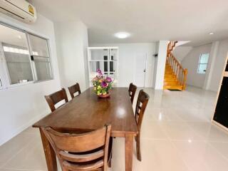 Spacious dining room with wooden table, flowers, staircase, and bright interior