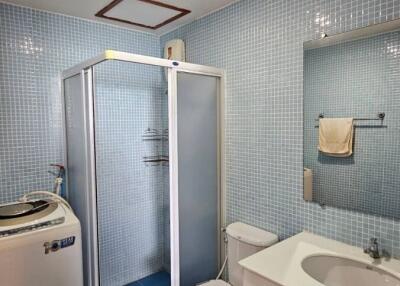 Modern blue tiled bathroom with shower, toilet, and sink