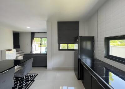 Modern and sleek living room with integrated kitchenette featuring black countertops and stylish furniture