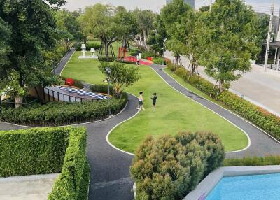 Lush communal garden with walking path and swimming pool in a residential complex