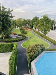 Lush communal garden with walking path and swimming pool in a residential complex