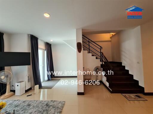 Spacious living room with modern staircase and natural lighting