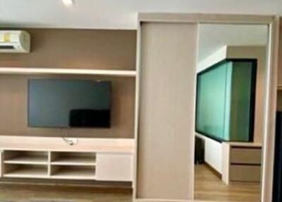 Modern living room with wooden flooring, integrated entertainment unit, and attached bedroom