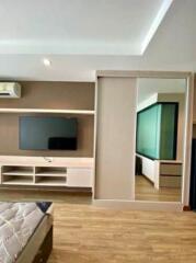 Modern living room with wooden flooring, integrated entertainment unit, and attached bedroom