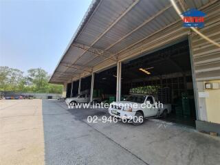 Industrial building exterior showing open garage space with vehicles