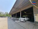 Industrial building exterior showing open garage space with vehicles