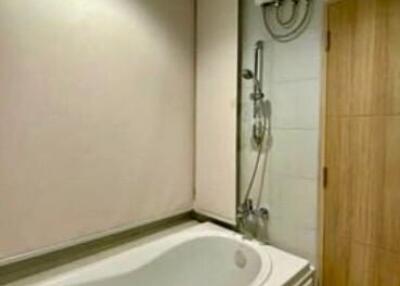 Modern, compact bathroom with bathtub and wooden door
