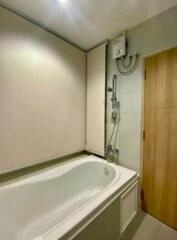Modern, compact bathroom with bathtub and wooden door