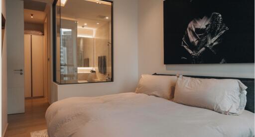 Modern bedroom with en-suite bathroom featuring glass partition and black and white wall art