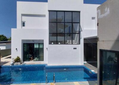 Modern two-story white residential building with a swimming pool