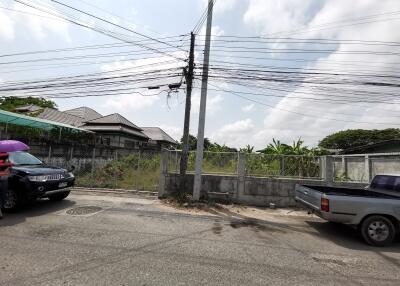 Outdoor street view in a residential area with visible power lines and parked vehicles