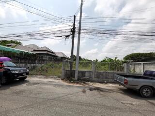 Outdoor street view in a residential area with visible power lines and parked vehicles