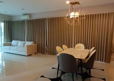 Modern living room with dining area, featuring elegant furniture and curtain