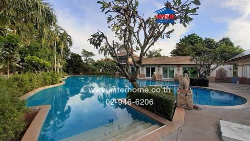 Spacious outdoor swimming pool with surrounding patio and lush garden in a residential property