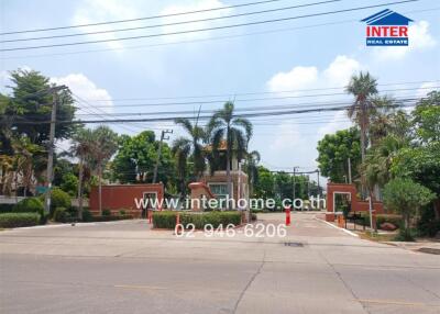 Gated community entrance with palm trees and clear blue sky