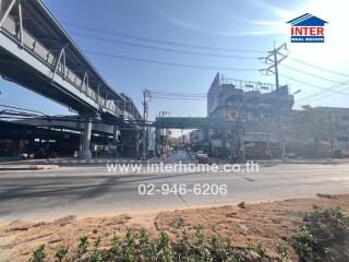 Busy urban street scene with overhead train tracks and commercial buildings