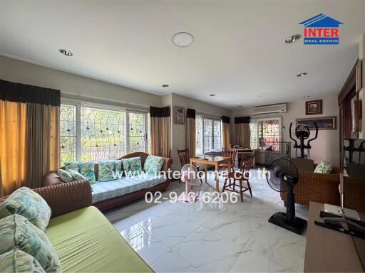 Spacious and well-lit living room with large windows and comfortable seating