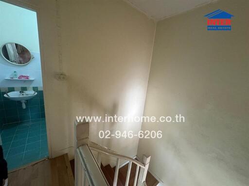 Bright staircase area leading to a small bathroom with blue tiles