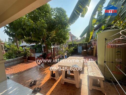 Spacious outdoor patio with lush greenery and seating area in a residential property