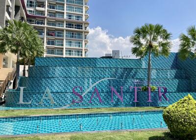 Luxurious outdoor pool area with decorative signage and lush greenery at La Santir condominium