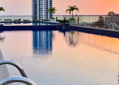 Sunset view over a swimming pool with a high-rise building in the background