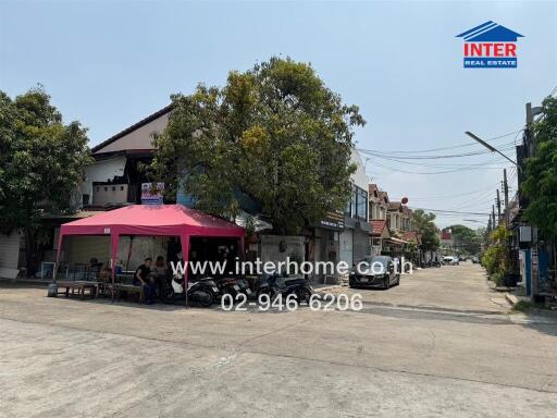 Urban street view showing a commercial property with a red canopy and busy street