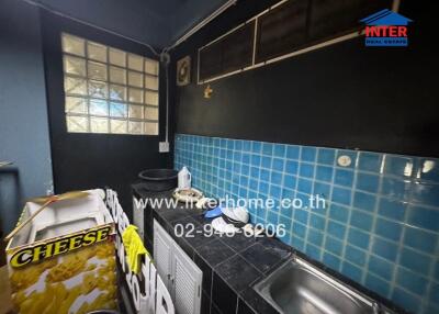 Cluttered kitchen with dark walls and blue tiles