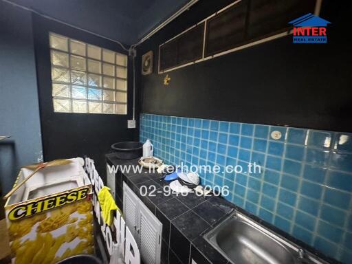 Cluttered kitchen with dark walls and blue tiles