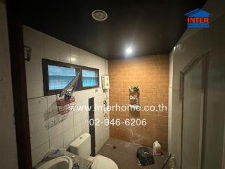 Compact bathroom with shower and tiled walls