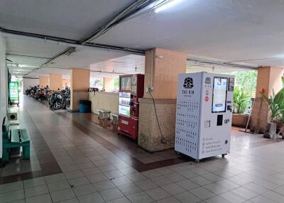 Covered parking area in a residential building with vending machines and motorcycles