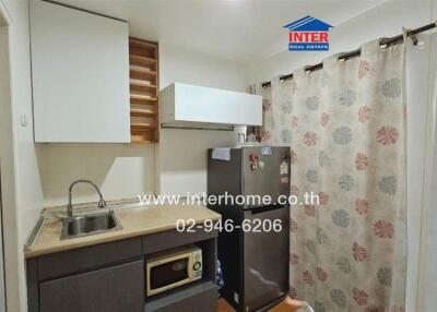 Compact kitchen with modern appliances and floral curtain divider
