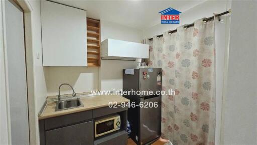 Compact kitchen with modern appliances and floral curtain divider