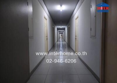 Long corridor in a residential building with multiple doors and overhead lighting