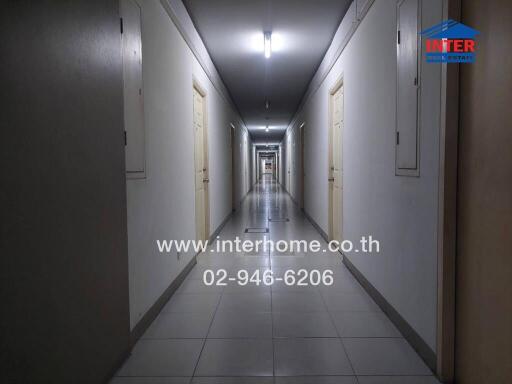 Long corridor in a residential building with multiple doors and overhead lighting