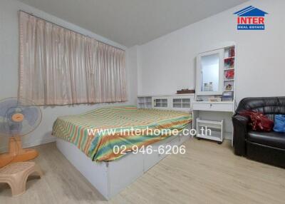 Spacious bedroom with a large bed, work desk, and comfortable seating