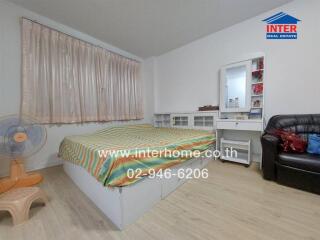 Spacious bedroom with a large bed, work desk, and comfortable seating